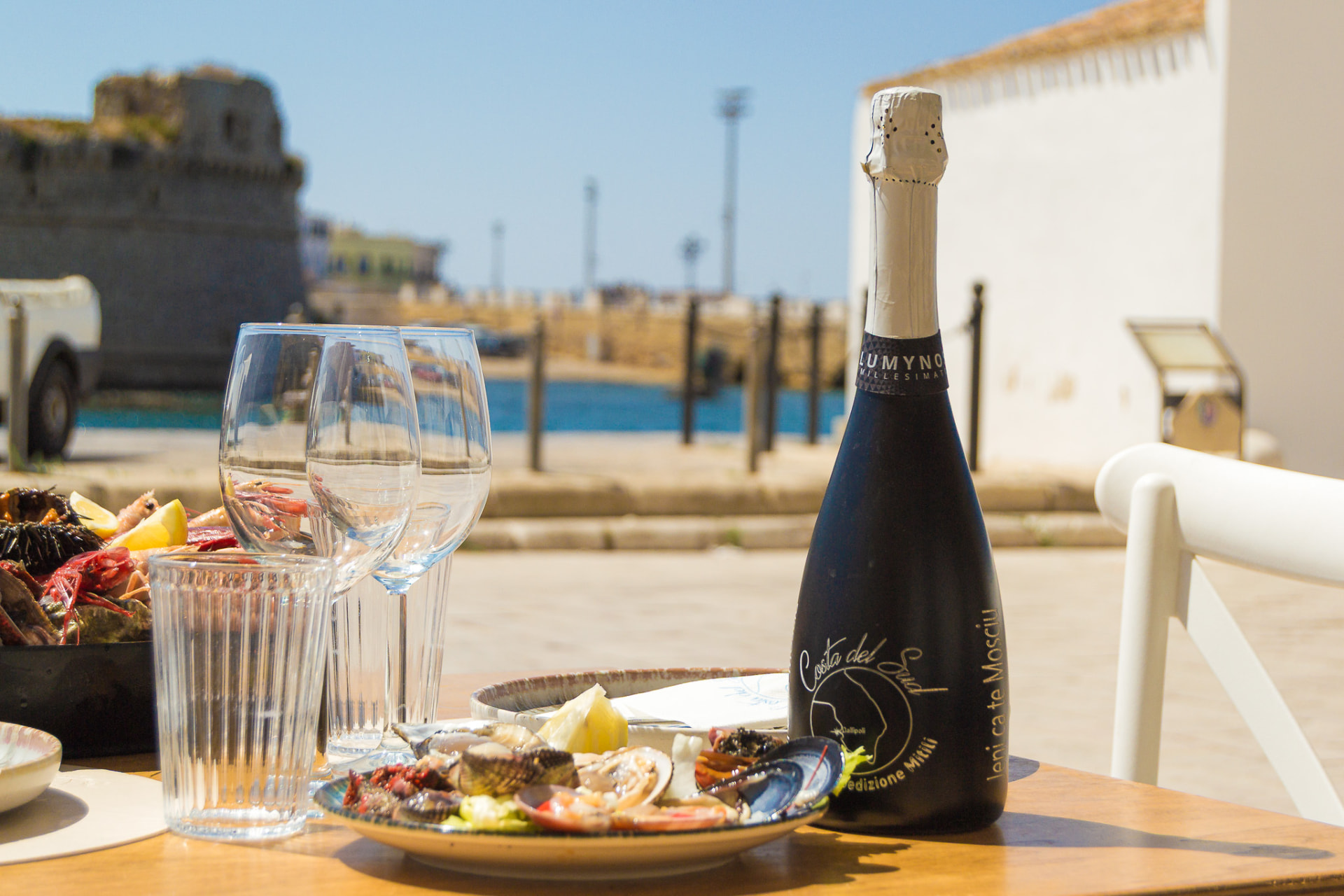 Tavolo apparecchiato con frutti di mare davanti al porto di Gallipoli